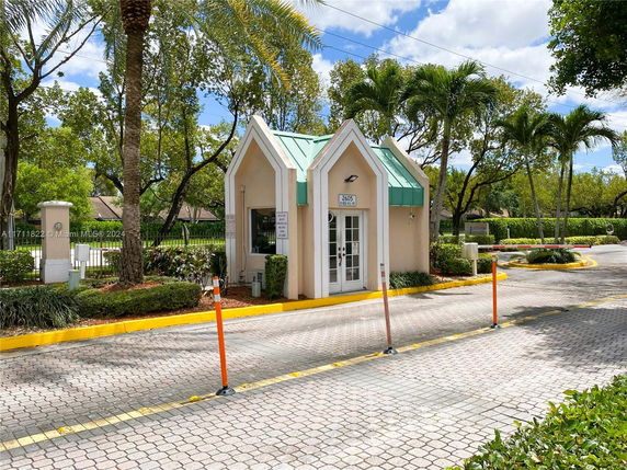Front view of a small security gatehouse with a green roof.