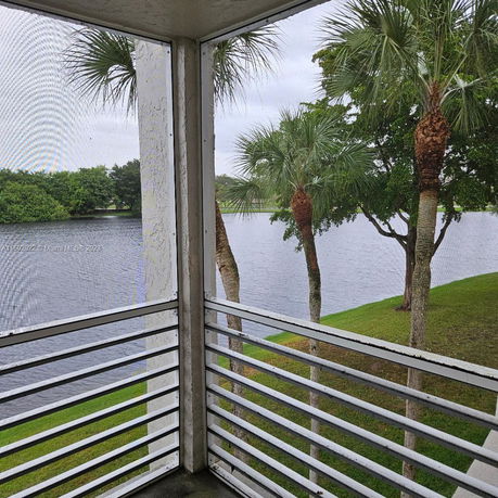 View from a screened balcony overlooking a lake and palm trees.
