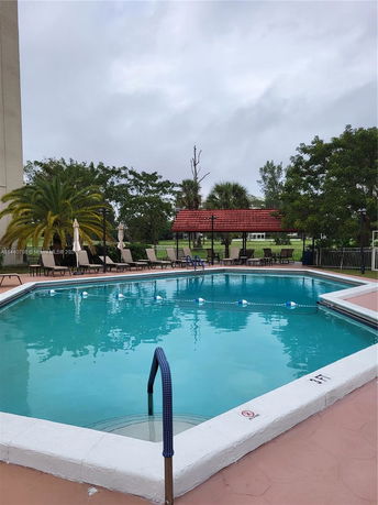 Outdoor swimming pool area with lounge chairs and a pavilion.
