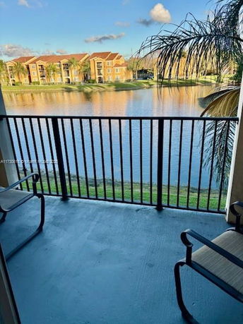 View from a balcony overlooking a lake with distant apartment buildings.