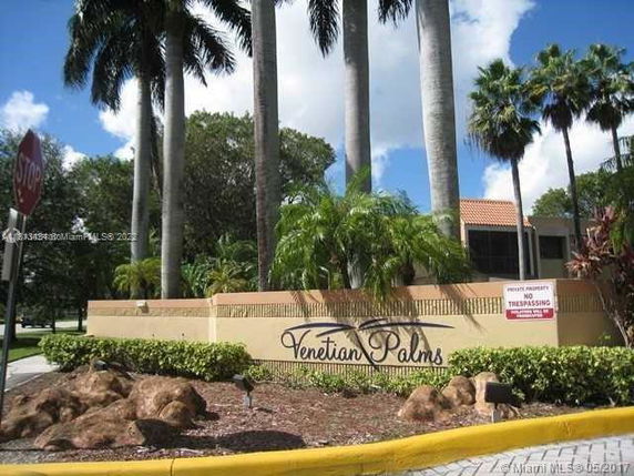 Front view of the entrance to a residential community with signage and palm trees.