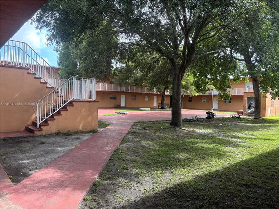 Outdoor play area with surrounding two-story building and trees.