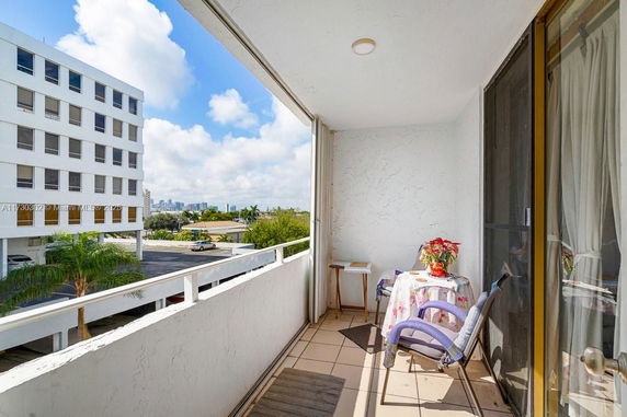 Balcony view with nearby building and distant city skyline.