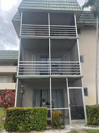 Front view of a multi-story building with balconies and a sloped roof.