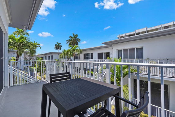 Outdoor view from a balcony overlooking neighboring buildings and palm trees.