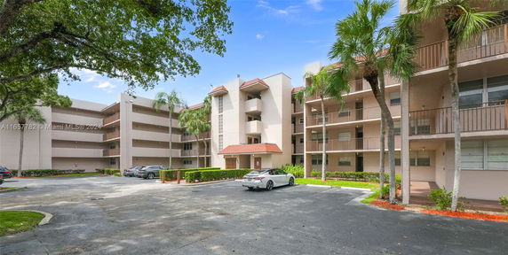 Front view of a multi-story apartment building with balconies and parking area.