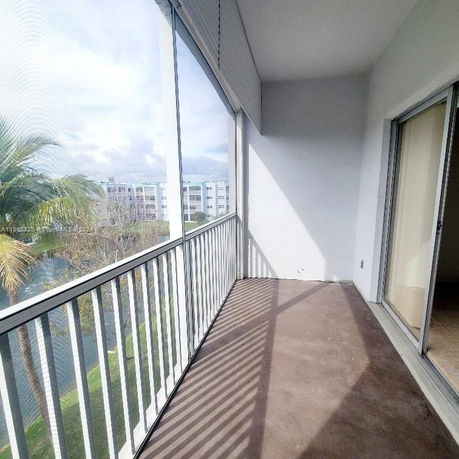 Balcony view with adjacent buildings and trees visible.