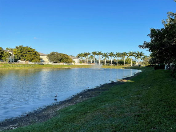 View of a pond with surrounding houses and palm trees.