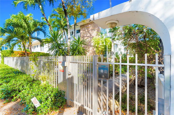 Front view of a building with a metal gate and lush greenery.