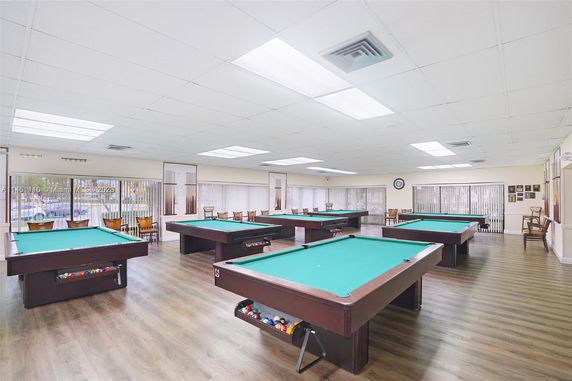 Room with multiple pool tables and chairs arranged around them.