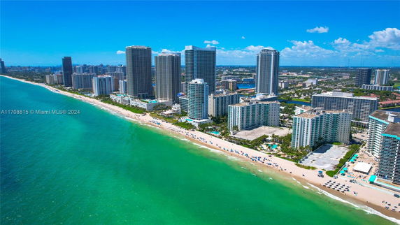 Aerial view of a coastal cityscape with tall residential buildings and a beachside area.