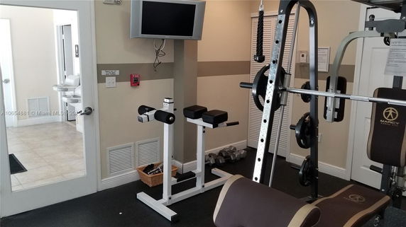 Indoor gym area with exercise equipment and a wall-mounted TV