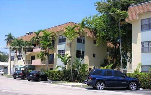 Corner view of a multi-story residential building with parking area in the front.