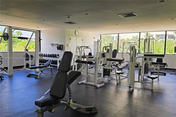 Gym area with various exercise equipment and large windows.