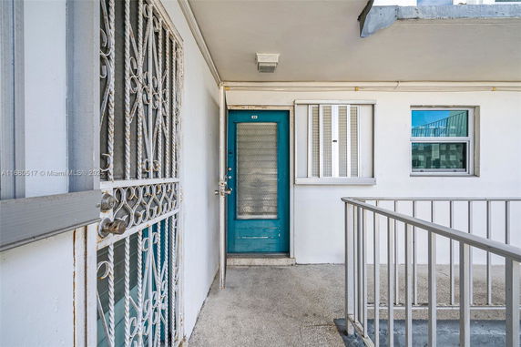 View of an apartment entrance with a blue door and metal security gate.