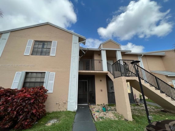 Front view of a two-story residential building with external stairs and shutters on windows.