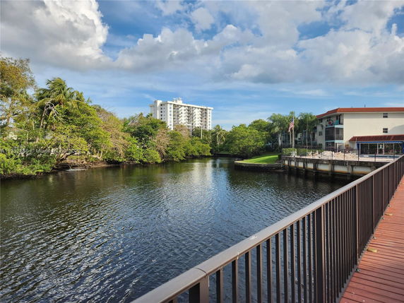 View of a building next to a river with lush greenery and another building in the background.