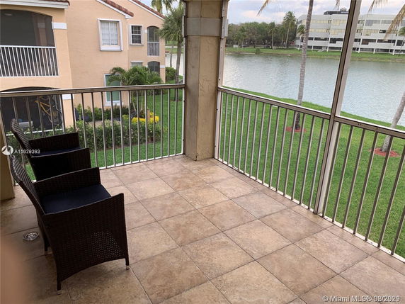 Balcony view overlooking grass and a water body with surrounding buildings