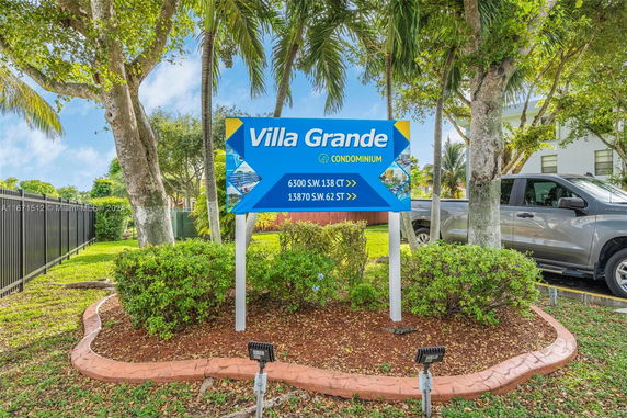 Outdoor sign for Villa Grande Condominium surrounded by trees and bushes.