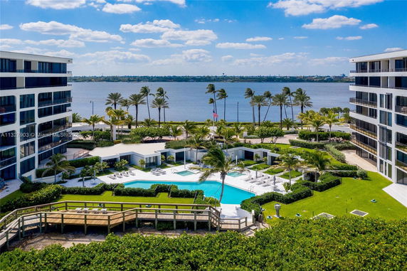 View of a residential complex with swimming pool, surrounded by landscaped gardens and flanked by waterfront buildings.