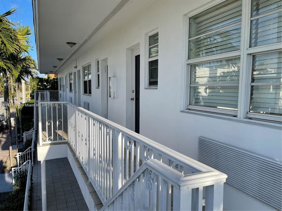 Exterior walkway of a two-story building with white railing and windows.