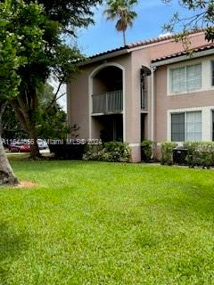 Front view of a two-story residential building with an arched balcony and tiled roof.