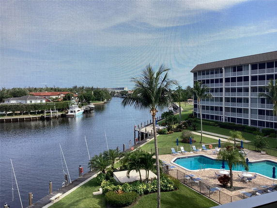 View of an outdoor swimming pool with buildings and waterfront canal.