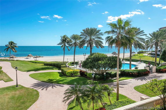 Panoramic view of a beachside area with palm trees and a swimming pool.