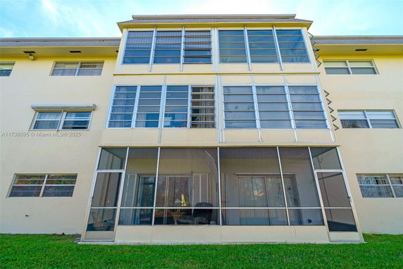 Front view of a multi-story building with large windows and screened balconies.