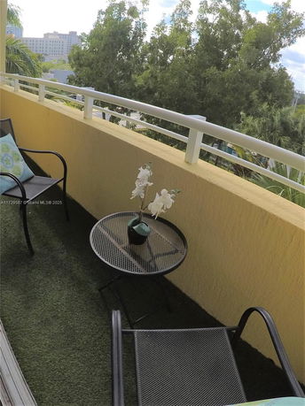 Balcony view with outdoor furniture overlooking trees and buildings.