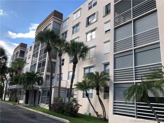 Front view of a multi-story residential building with palm trees.