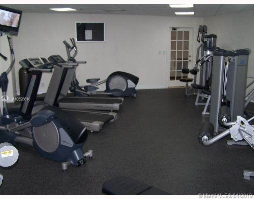 Room with gym equipment including treadmills and weight machines.