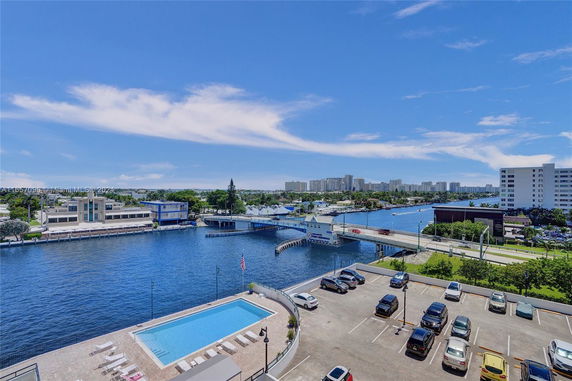 Panoramic view of waterfront area with a parking lot and swimming pool.