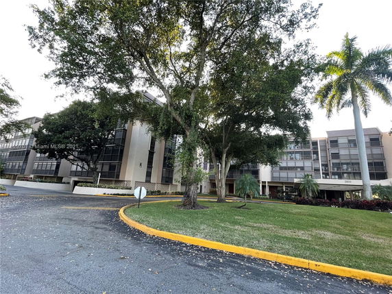 Front view of a multi-story building with large windows and surrounding trees.
