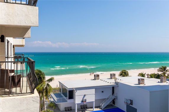 View of the ocean and beach from a building balcony.