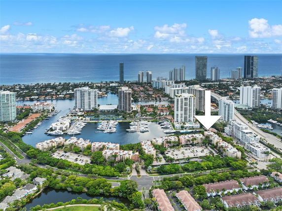 Aerial panoramic view of a coastal city with high-rise buildings and a marina.