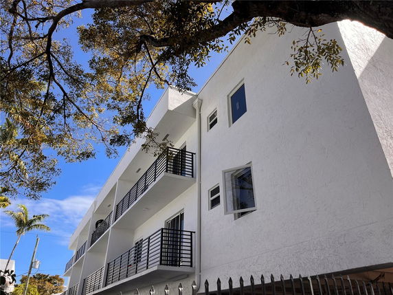 Side view of a multi-story building with balconies and a white exterior.