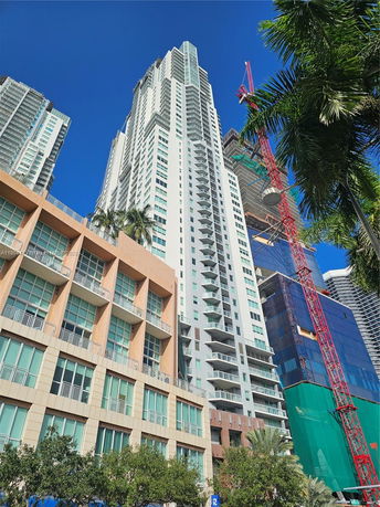 Front view of a tall skyscraper with balconies and glass windows.