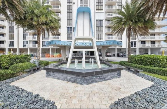 Front view of a multi-story building with a decorative fountain and entrance canopy.