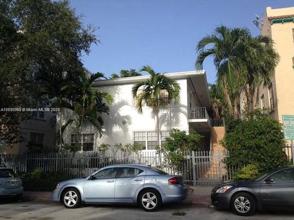 Front view of a two-story building with a flat roof and a fenced entrance.