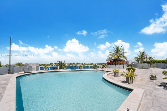 Outdoor swimming pool area with surrounding planters and view of the sky.