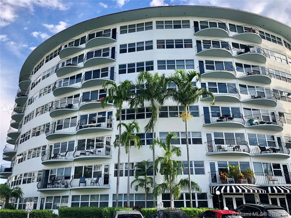 Front view of a multi-story curved building with numerous balconies.