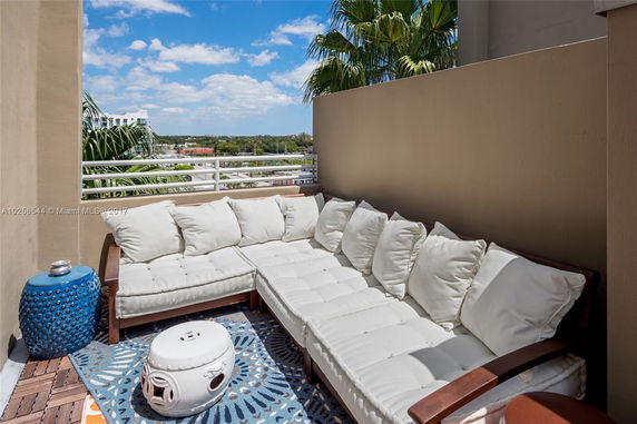 Rooftop area with white cushioned seating and decorative side tables.