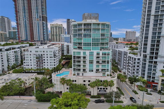 Front view of a high-rise building with balconies and a swimming pool on an upper level.