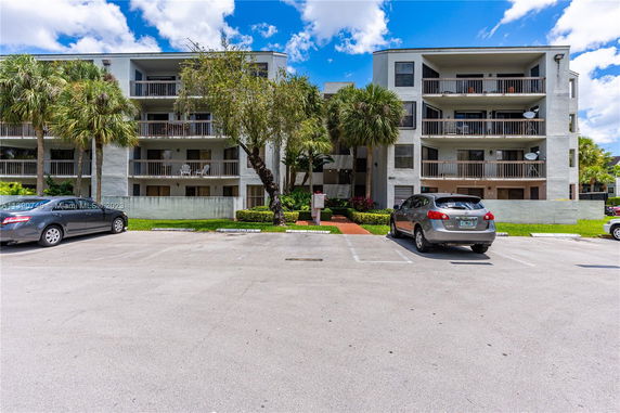 Front view of a multi-story residential building with a parking area.