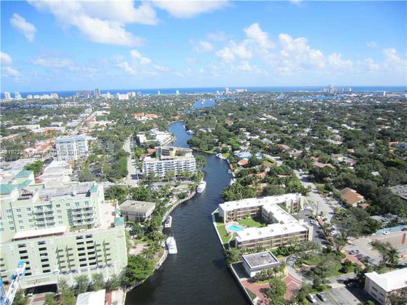 Aerial view of a cityscape with river, buildings, and ocean in the background.