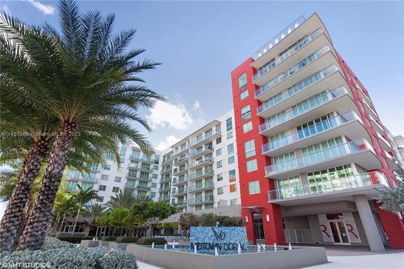 Front view of a multi-story modern building with red and white exterior and numerous balconies.