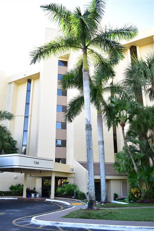 Front view of a multi-story building with palm trees in front.