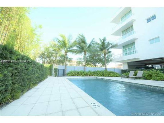 Outdoor swimming pool area beside a multi-story building.