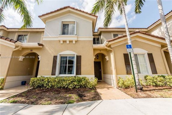 Front view of a two-story residential building with a decorative archway and shutters.